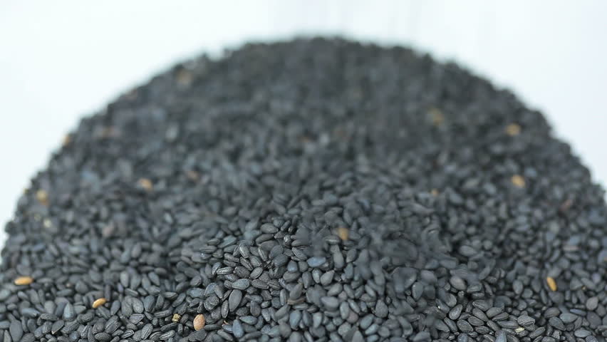 Pouring sesame seeds into a glass.