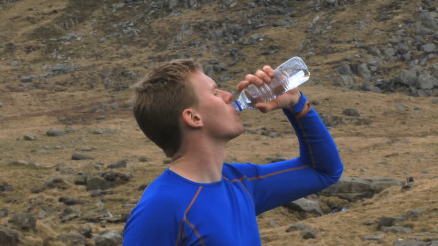 CLOSE UP of male drinking bottle of water in nature