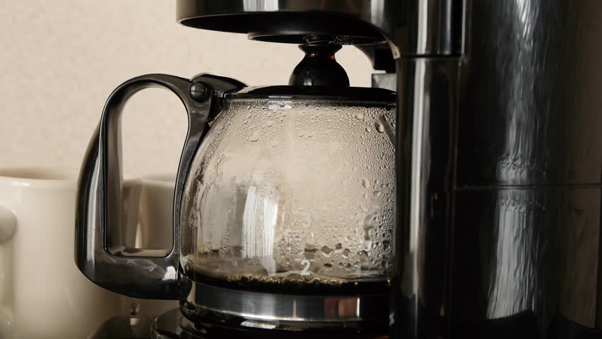 Close-up shot of coffee brewing in coffee maker and flowing in to carafe