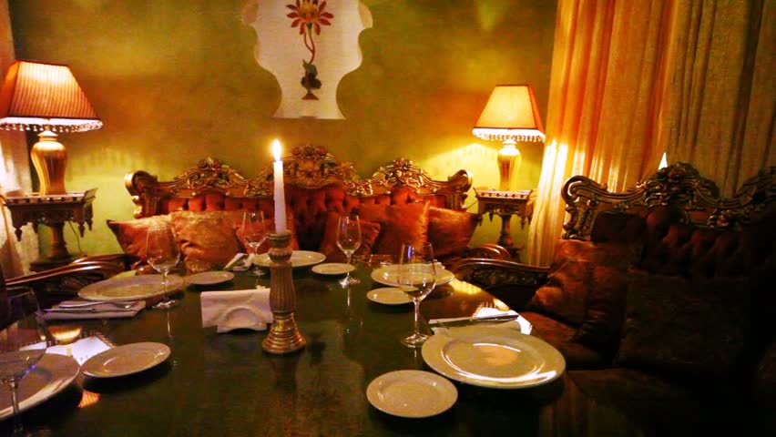Decorated table with candle stands surrounded with sofas with small pillows