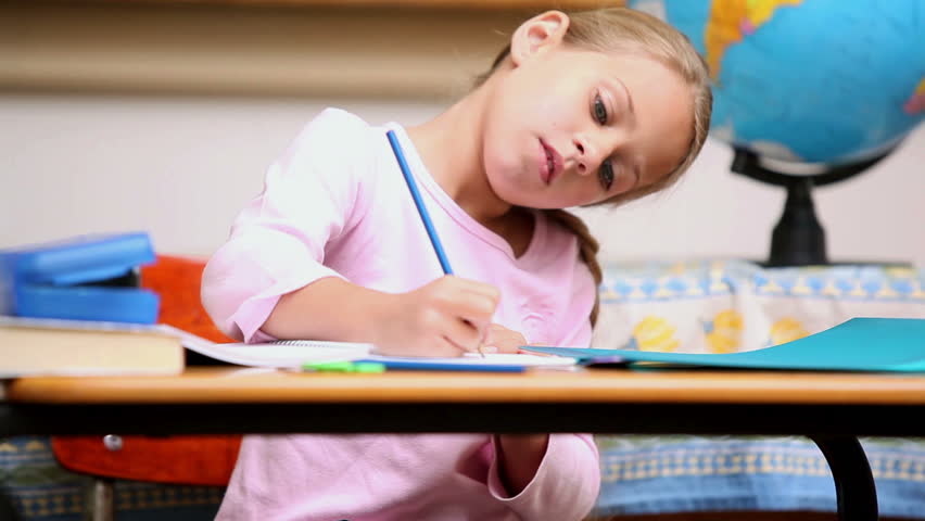 Pupil writing on a notebook in the classroom