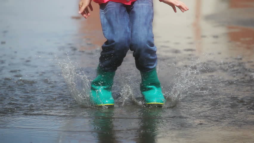 Girl running, jumping and splashing in the middle of the puddle