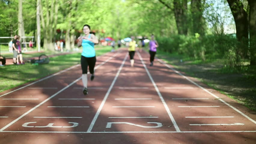 Three young women running on track lane, slow motion
