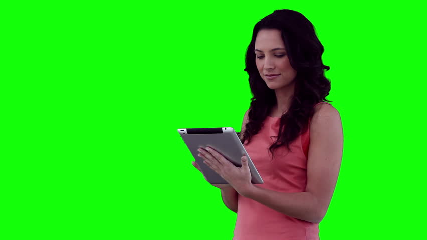 Woman happily using a tablet computer against a green background
