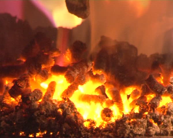 closeup of burn straw pellets in boiler. flames and fire details. ecologic fuel use for house heating.