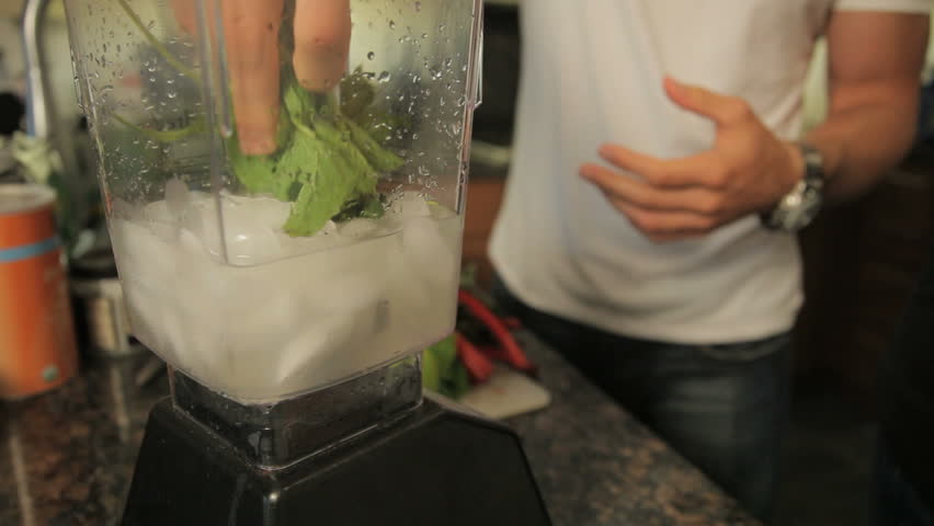 person mixing veggies with ice in blender