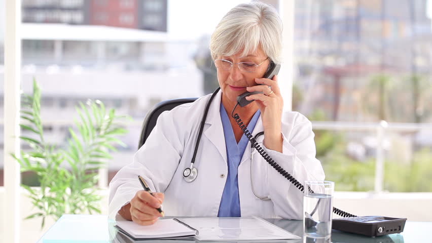 Smiling doctor talking on the phone while sitting in a bright office