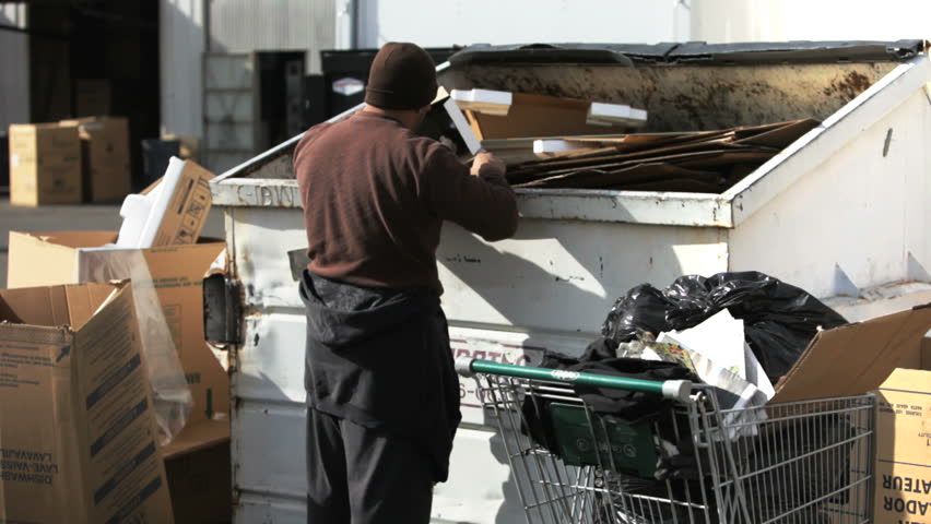 homeless man rummaging through a dumpster