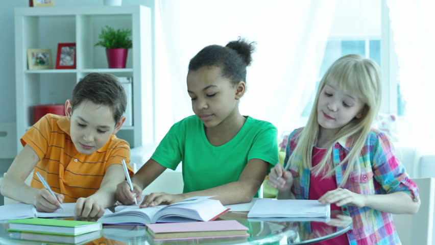 Diligent pupils helping each other while working on their essays for school