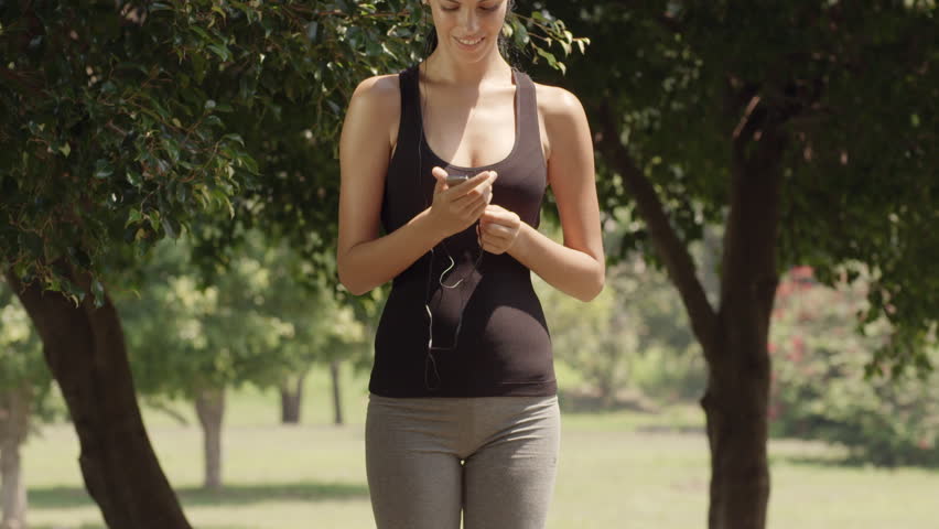 Sport and music, beautiful young woman with mp3 player listening to tunes and running in city park