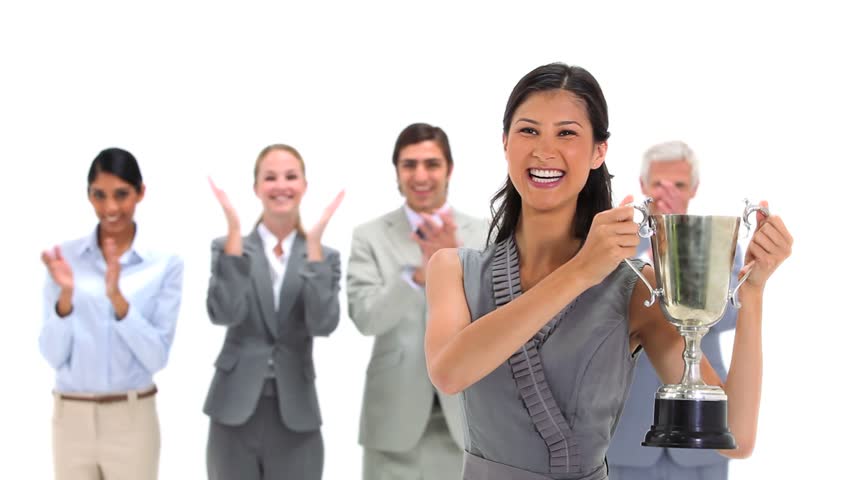 Woman holding a trophy with co-workers applauding against a white background