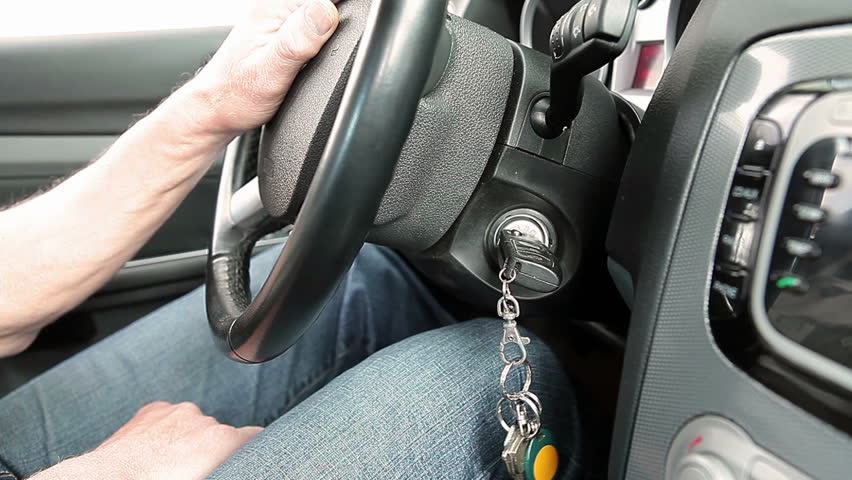 Man turning ignition key in car. Close up view