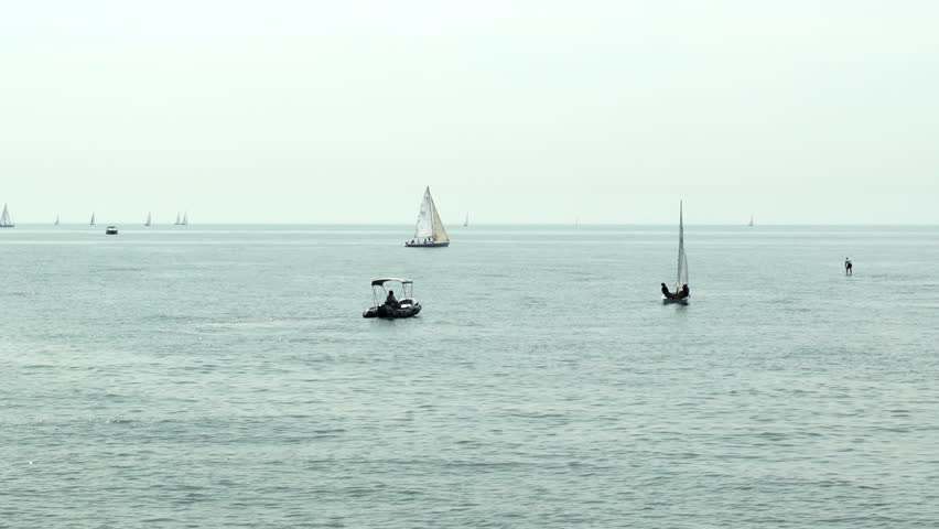 On a warm hazy day various watercraft out on the lake. Not graded.