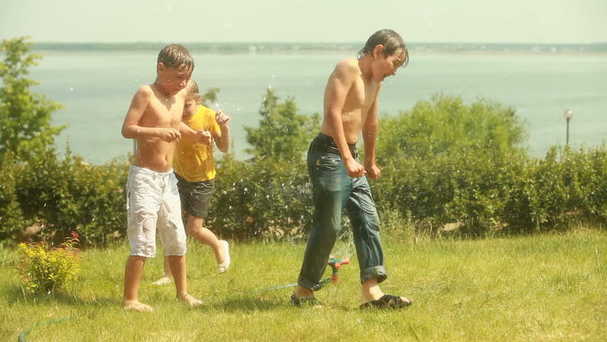 Kids soaking wet running around a working sprinkler