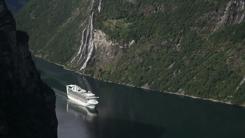 Cruise ship approaching the Geiranger Fjord in a beautiful scenery. To the right of the ship the Seven Sisters Waterfall