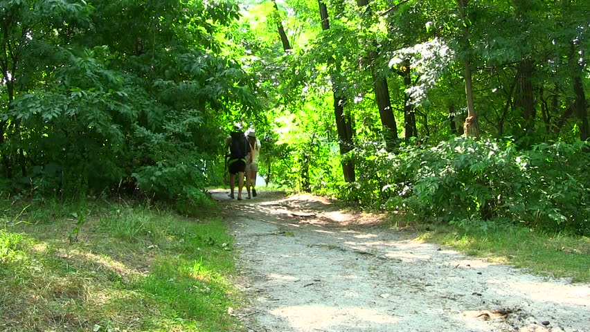 young man and  girl go on a footpath in the wood