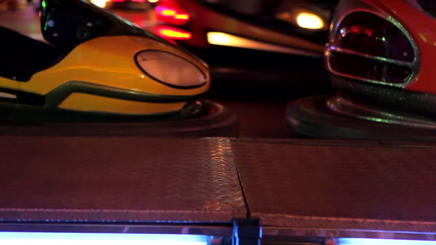 Bumper cars ride in motion with flashing colorful lights in a fun fair at night.