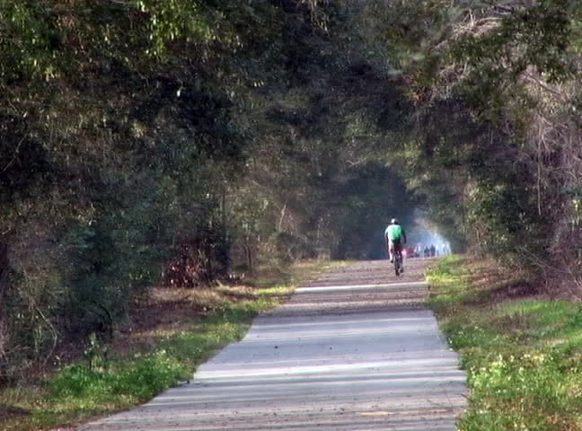 A bicyclist rides down the paved trail.