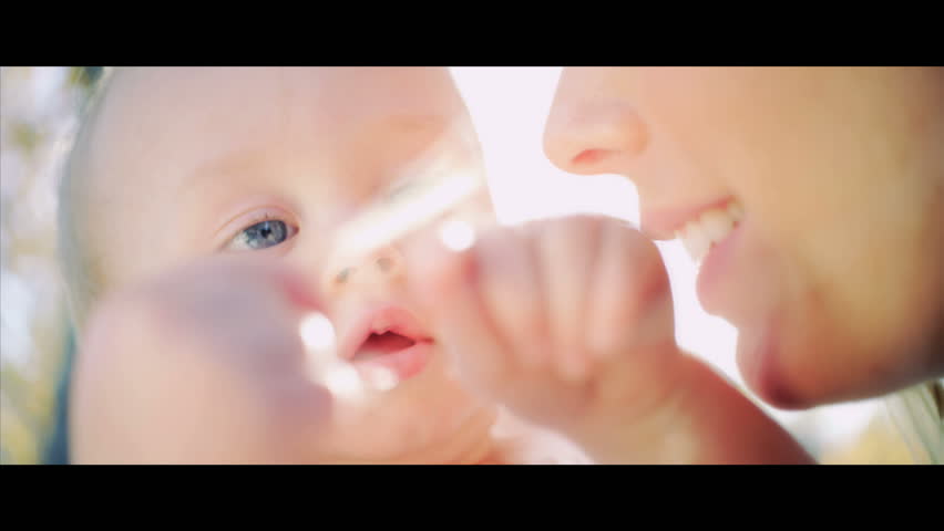 Happy baby supported by his mother as he practices walking shot in 5K widescreen RED EPIC