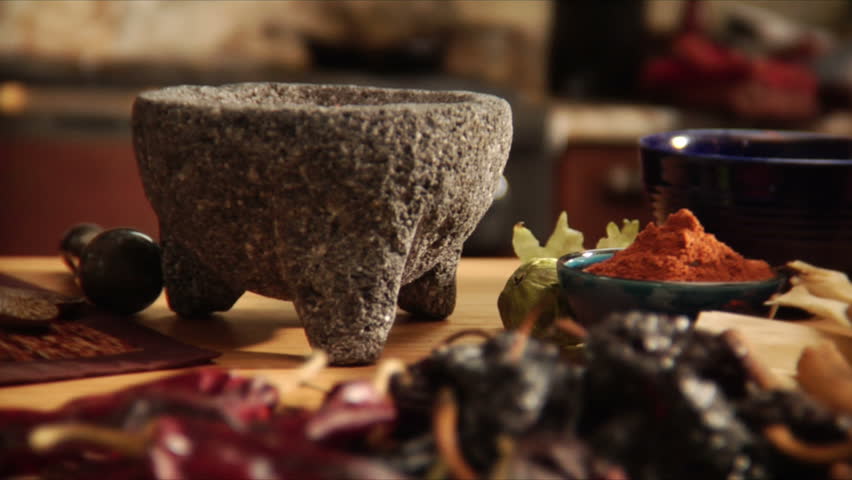 Chef crushing mexican spices with mortar and pestle