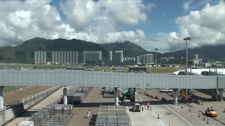 Hong Kong, China - CIRCA April, 2007: Different vehicles are in motion on the tarmac of the Hong Kong International Airport during a beautiful day with clouds rolling over the surrounding mountains