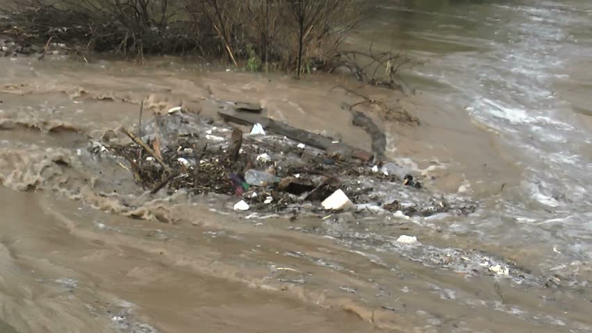 Plastic bottles, wood, flotsam, trash, swept into pile, whirl around in an eddy formed by flash flood caused by heavy rains. 1080p
