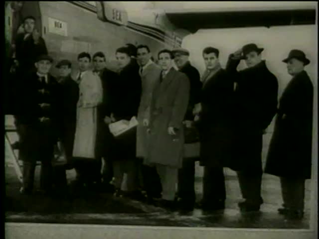 A photograph of Manchester United Football team near an airplane in Munich-Riem Airport, Munich, West Germany circa February, 1958 - MGM PICTURES, UNIVERSAL-INTERNATIONAL NEWSREEL, USA, filmed in 1958
