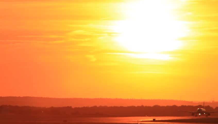 Passenger jet plane taking off runway in sunset