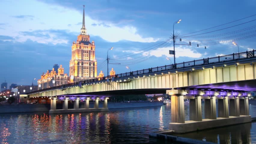 Ship floats near Novoarbatsky bridge with skyscrapers of Stalin era and Moscow City at evening