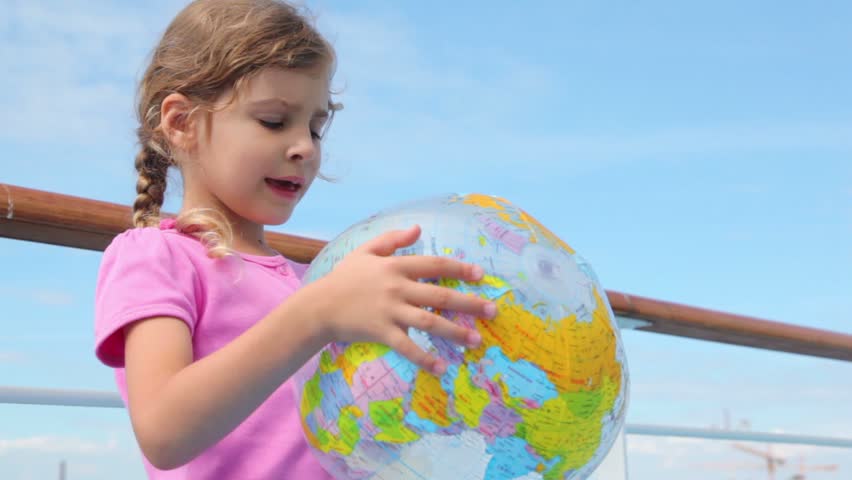 Little girl hold inflated ball with earth texture and reads aloud near railing