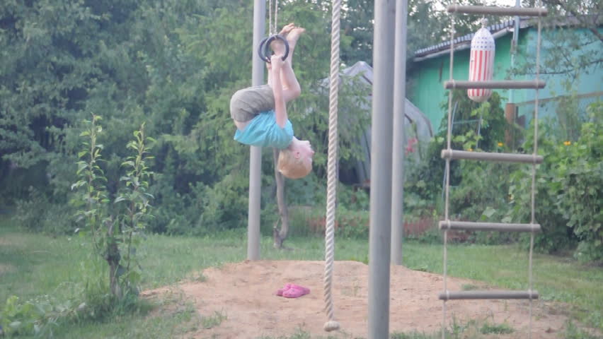 young cute boy exercising on gymnastic rings