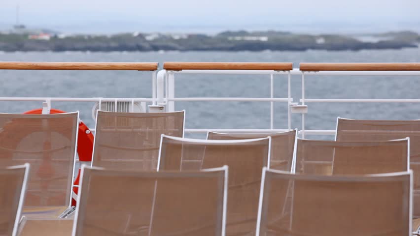 Chaise lounges stand on ship deck against sky and the horizon