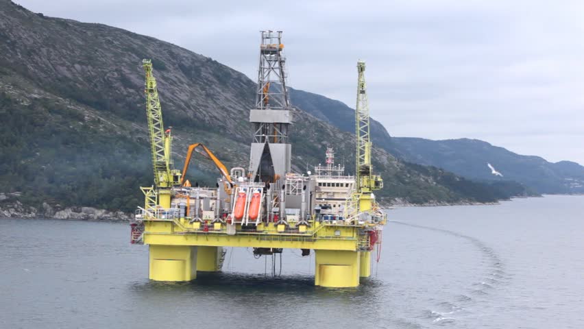 Seagulls fly over water near drilling platform in gulf of Stavanger
