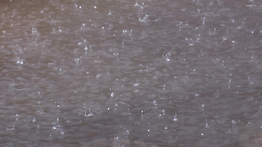Raindrops dance, bounce, as they hit puddle during heavy rainfall. 1080p