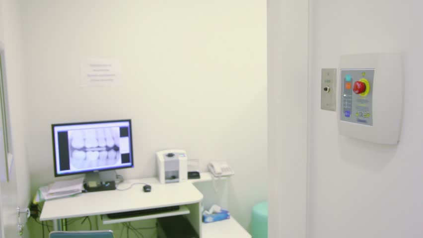 Nurse comes out of room, closes door and pushes button for x-ray photography, then comes back