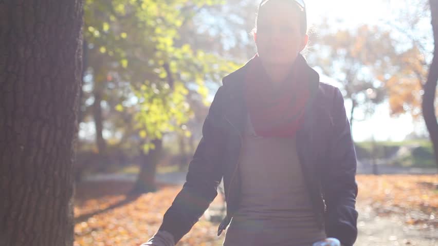 Young woman riding on bike in autumn setting.
