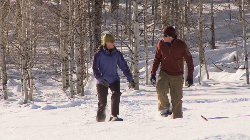 Couple walking through the snow with snow shoes on
