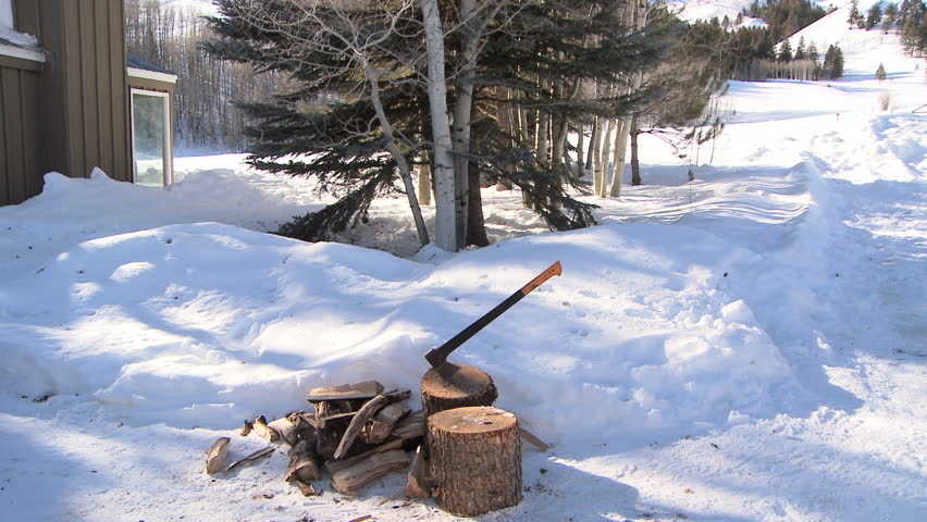 Man putting chopped wood into wheel barrel in the snow