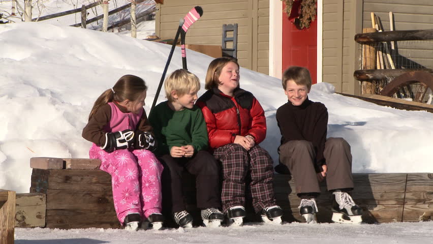 Four young kids play hockey on backyard ice rink