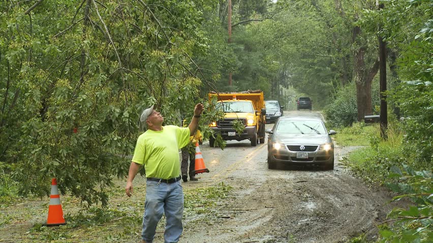 NEW ENGLAND - CIRCA SEPTEMBER 2011: Storm damage -- Utility workers directing cars around downed trees and power lines