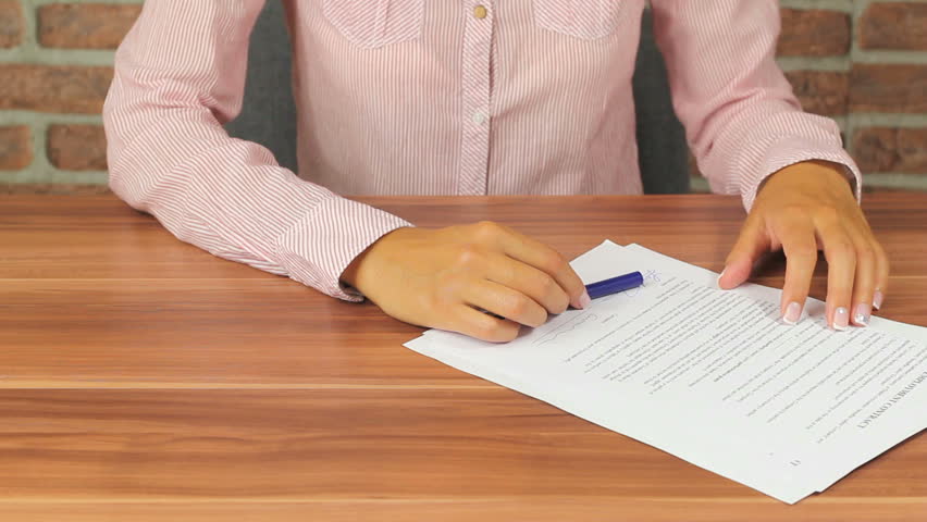 Woman Signing contracts - putting her signature on a document using a fountain pen