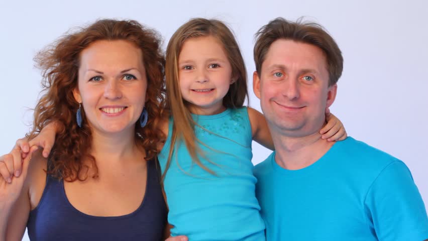 father with mother hold daughter who smiles and puts out tongue close up
