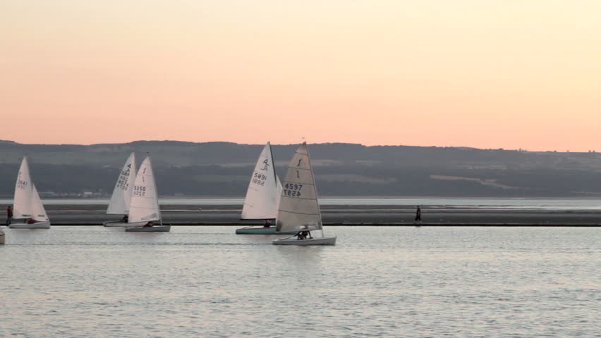 WEST KIRBY, WIRRAL/ENGLAND - AUGUST 9: Sail boats race across lake at sunset on August 9, 2012 in West Kirby. The Marine Lake is a man made coastal lake fed by the sea at high tide.  