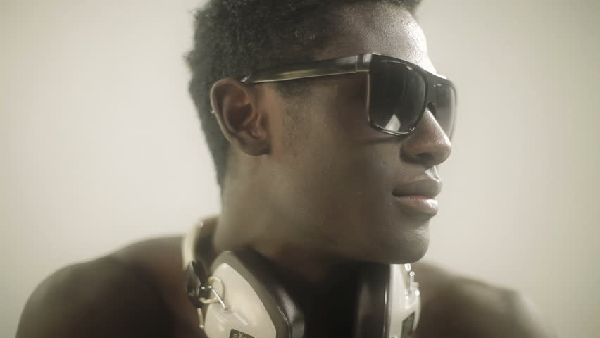 young african guy waving and dancing with a cool attitude, removing his glasses and looking to the camera