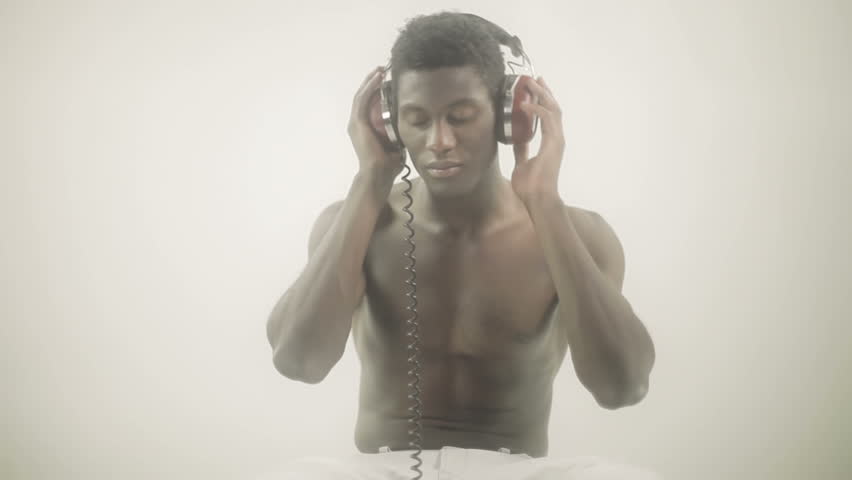 young african guy waving and dancing with a cool attitude with headphones while sitting
