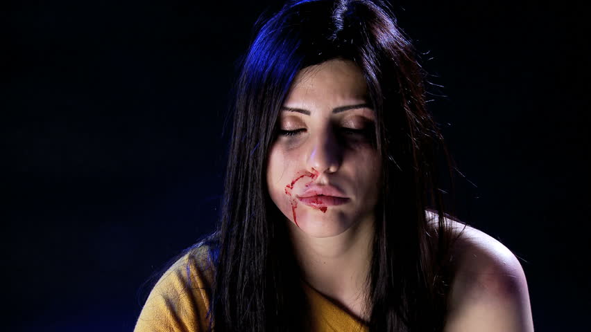 Beautiful woman cleaning blood from face after abuse and domestic violence