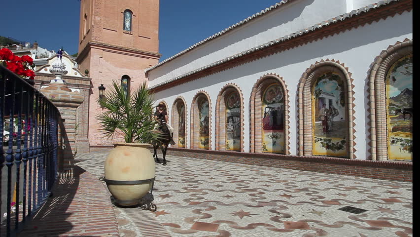 Man and woman riding a horse through a village in Andalusia, Spain