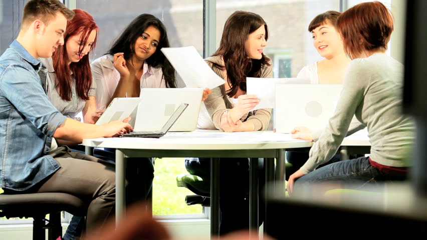 Class of male and female young classmates working on computer with Caucasian teacher in university information hub