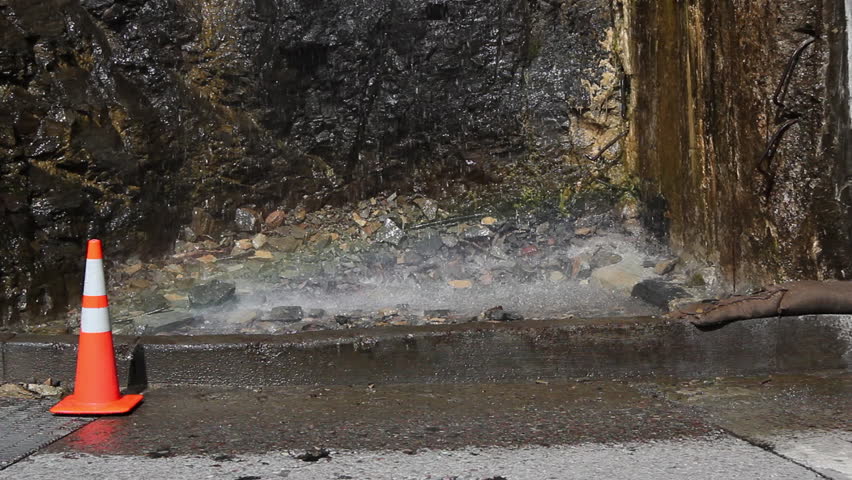 A rainbow created from water splashing onto the ground with a caution cone