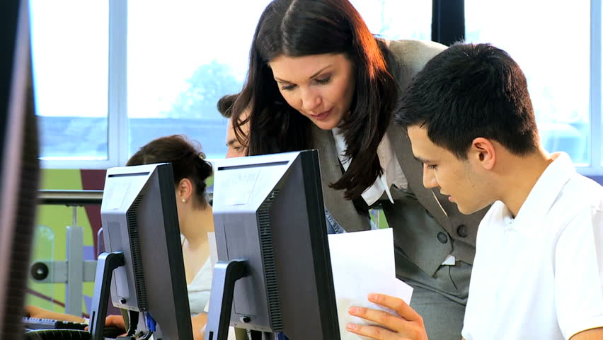 Caucasian female classmate using online computer degree exam in college classroom